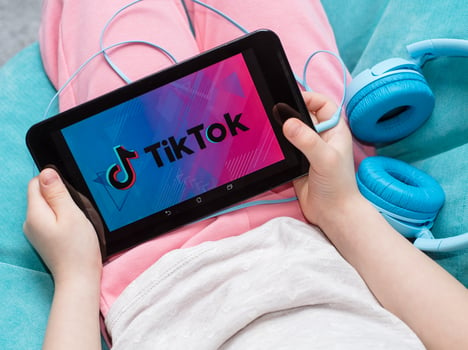 teen holding tablet with TikTok logo on the screen