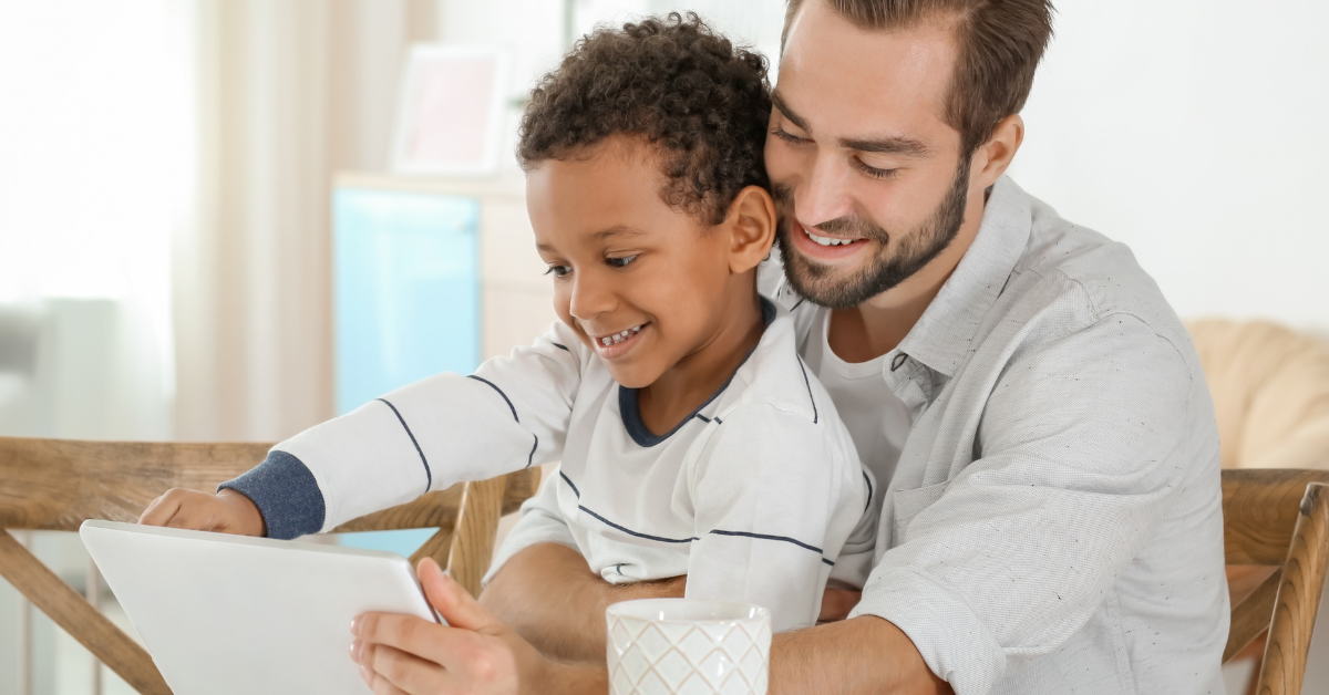 young boy and father playing with tablet together