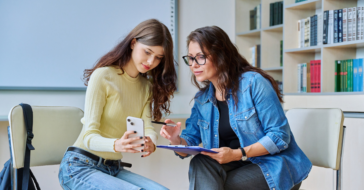 School counselor discussing online safety with a teen student using a smartphone