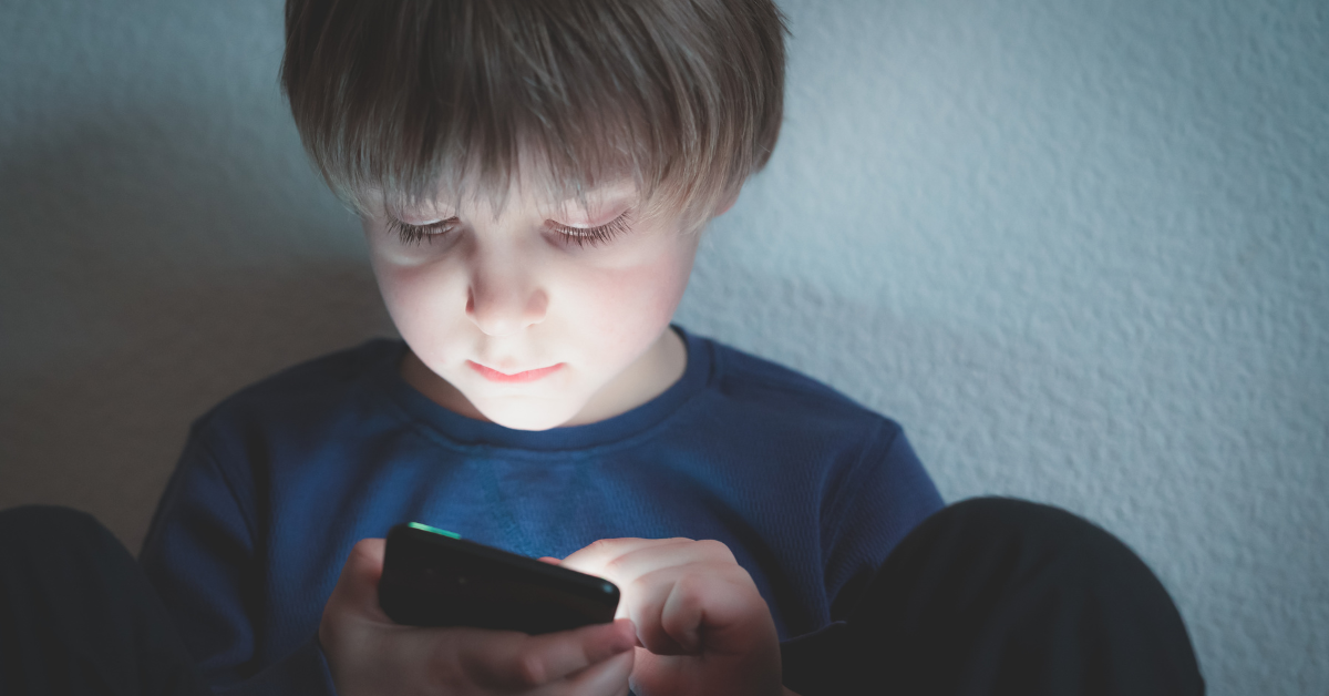 Young boy sitting alone using cell phone