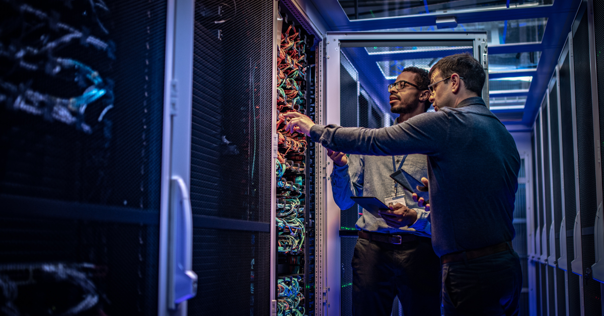 two men examining a computer server in a server room