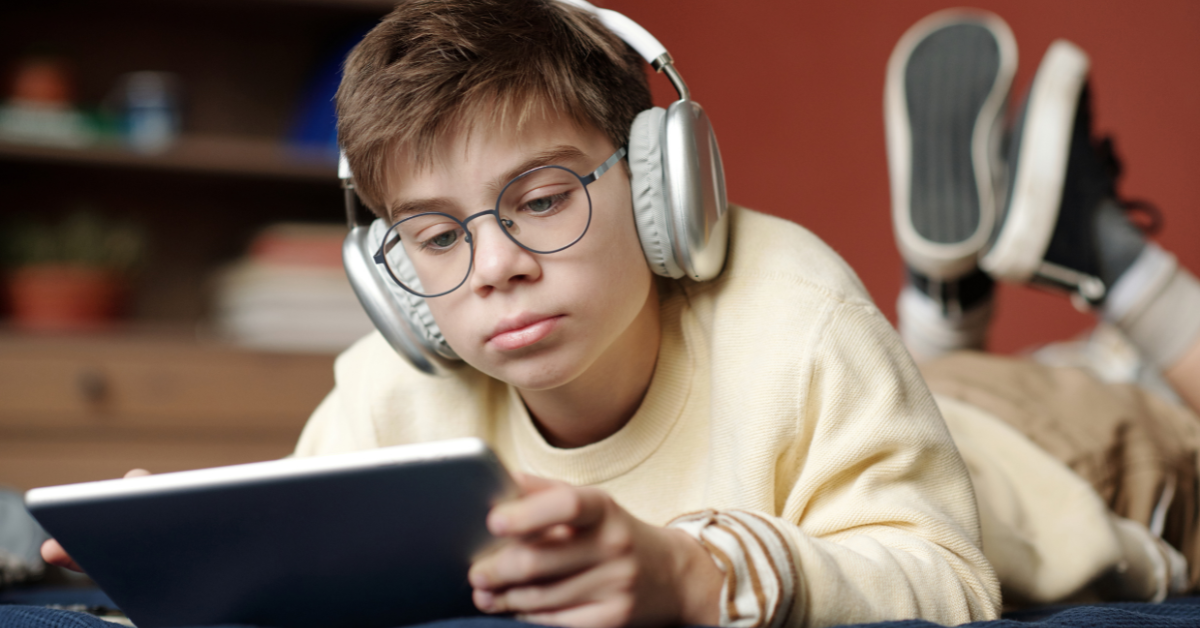 Young boy wearing headphones while looking at tablet