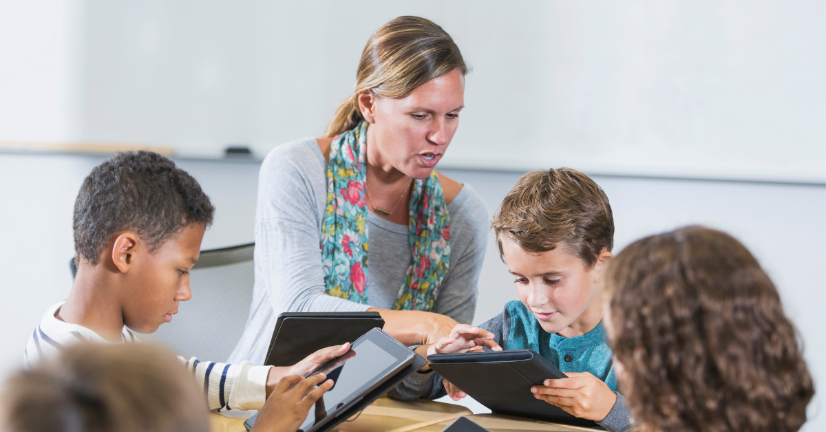 teacher helping a young student on a tablet device